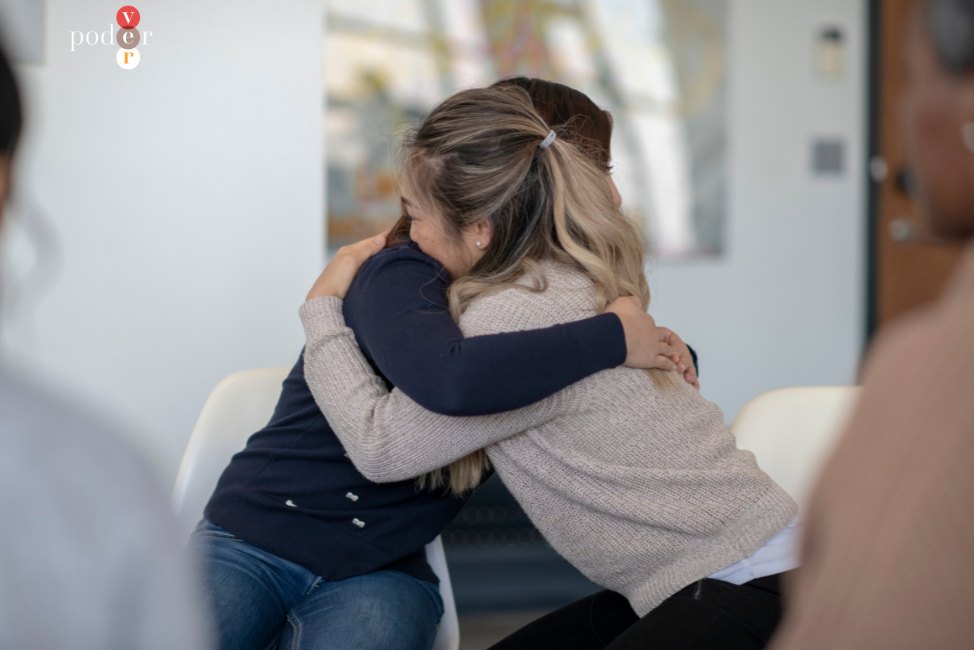 Dos mujeres se abrazan en un círculo de personas